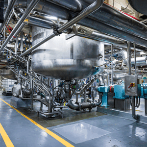 Stainless steel industrial tanks and piping inside a food processing facility.