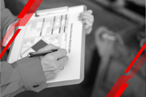 Person writes on a clipboard with a pen, filling out a form up close.