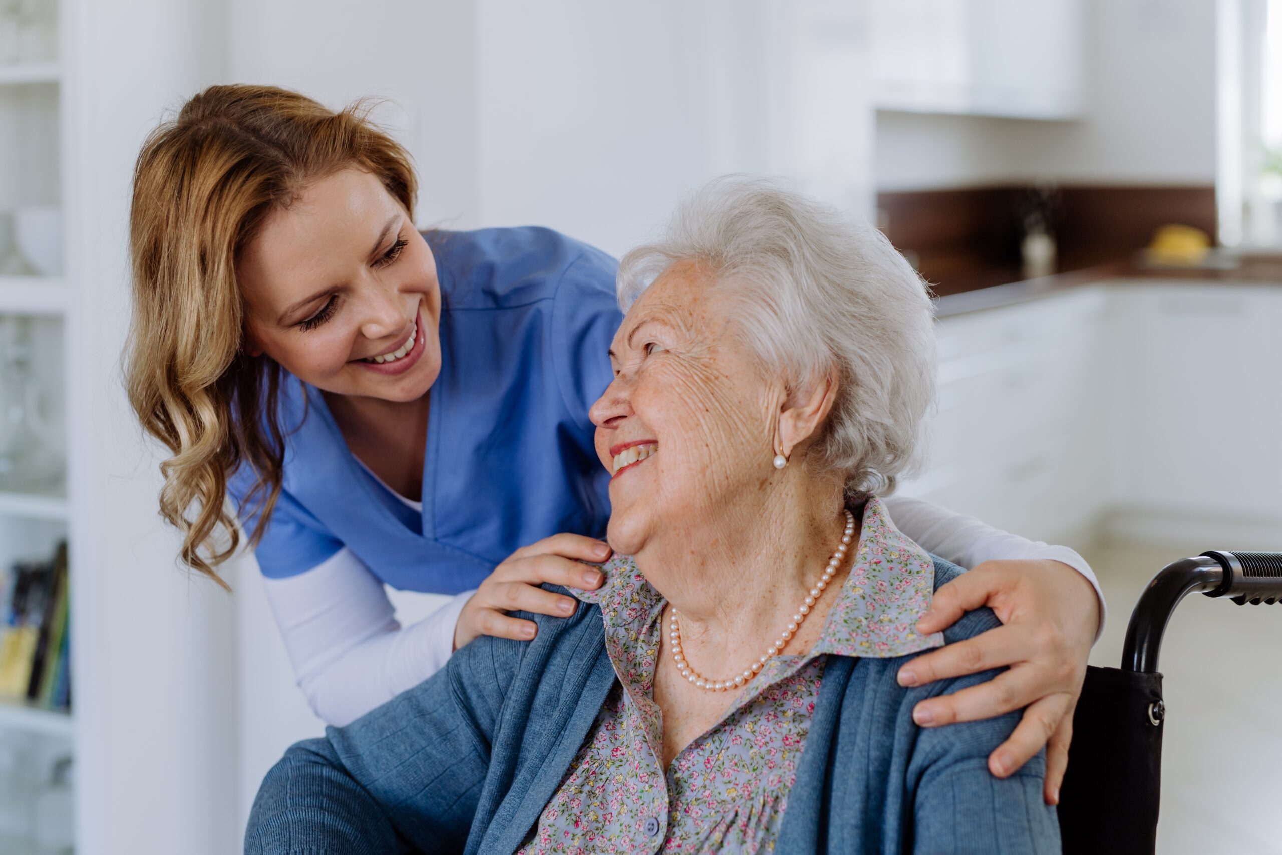 Nurse smiling with elderly women in wheel chair smiling 